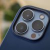 iPhone 13 Pro Max camera array with blue Magsafe case, blurred background with houseplants out of focus.