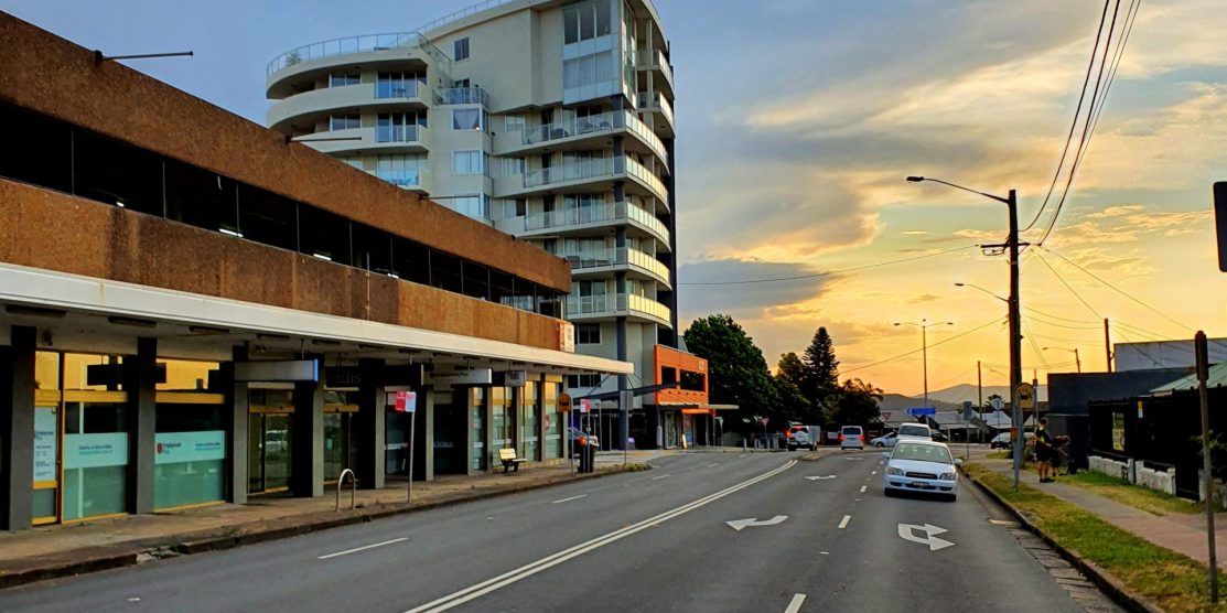 Image shows Alto apartments at Charlestown NSW, and Charlestown Road, a car can be seen in the left lane pulling up to the pedestrian crossing between Hilltop Plaza and Service NSW building. also near Matara Hotel.